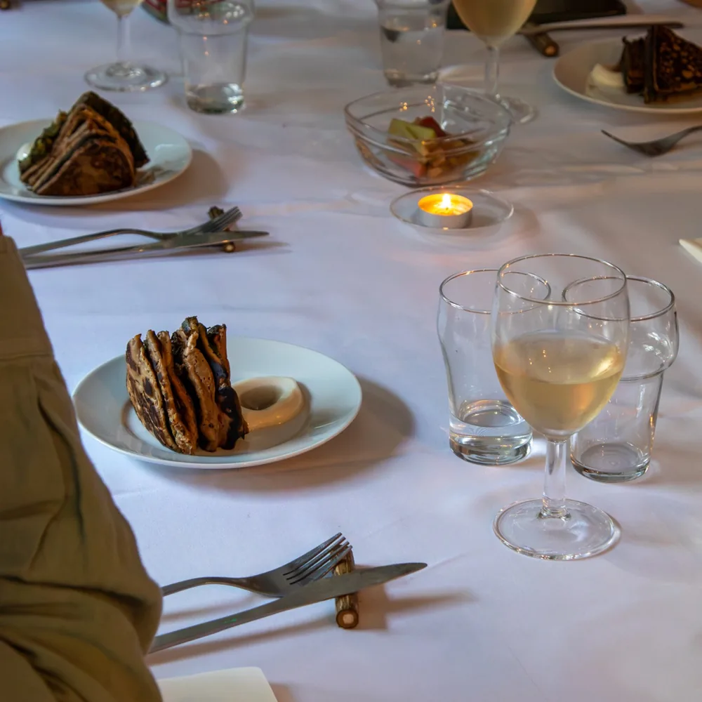 Gedekte tafel met kaarslicht, wijn en een gerecht op houten bestekhouders